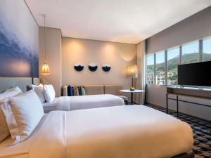 a hotel room with two beds and a flat screen tv at Pullman Cape Town City Centre in Cape Town