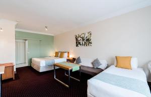 a hotel room with two beds and a couch at The Henry Parkes Tenterfield in Tenterfield +76 photos