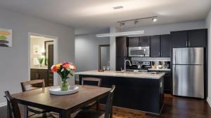 a kitchen with a table and a stainless steel refrigerator at Downtown Dallas CozySuites with gym #1 in Dallas