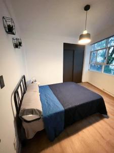a bedroom with a bed with a blue blanket and a window at Departamento Azul Roma in Cedro