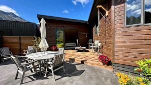 a patio with a table and chairs and an umbrella at Hawkshead Boutique Studio & Gardens in Makarora