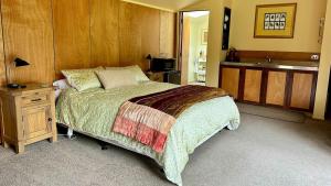 Hawkshead Boutique Studio & Gardens في ماكارورا: غرفة نوم بسرير كبير ومغسلة