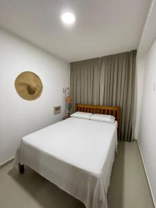 ein Schlafzimmer mit einem großen weißen Bett in einem Zimmer in der Unterkunft Apartamento com jardim em condomínio resort in Parnamirim