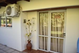 a door with a window and a vase with flowers at Sampa Pacha Complejo de Cabañas in Bialet Massé