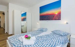 a white bedroom with a bed with a flower on it at Nice Home In Privlaka in Glavan