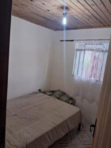 a small bedroom with a bed and a window at Pousada da Lu in São Francisco do Sul