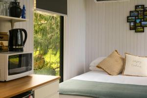a kitchen with a bed with a microwave and a window at Ryan's Ranch by Tiny Away in Belgrove