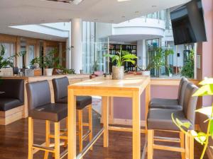 a restaurant with a wooden table and chairs at Atomis Hotel Munich Airport by Mercure in Oberding