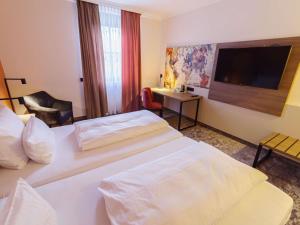a hotel room with two beds and a flat screen tv at Atomis Hotel Munich Airport by Mercure in Oberding +108 photos