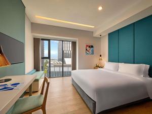 a bedroom with a large white bed and a desk at Novotel Living Saigon South in Ho Chi Minh City