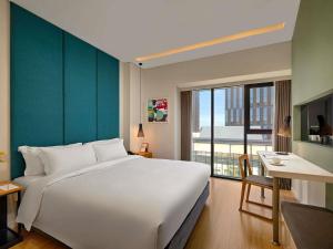 a bedroom with a large white bed and a large window at Novotel Living Saigon South in Ho Chi Minh City