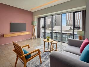 a living room with a couch and a tv at Novotel Living Saigon South in Ho Chi Minh City