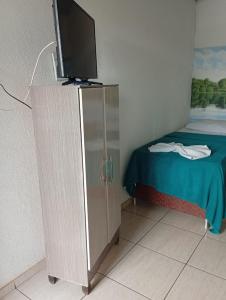 een slaapkamer met een bed en een televisie op een kast bij Hotel Indubrasil Campo Grande LDTA in Campo Grande