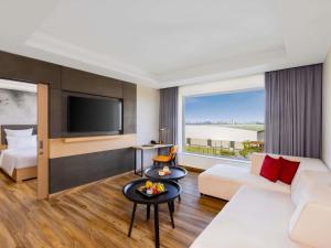a hotel room with a couch and a tv at Novotel Jaipur Convention Centre in Jaipur