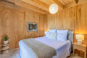 a bedroom with a bed with a wooden wall at The Gatehouse - Tata Headlands in Tata Beach