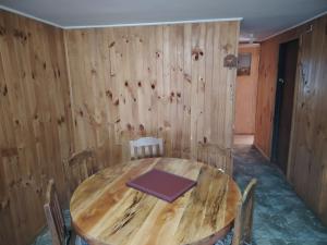 a wooden table and chairs in a room with a wooden wall at Cabañas Del Monte 3 in Melipeuco