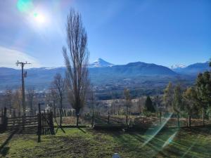 a view of the mountains from a yard with a fence at Cabañas Del Monte 3 in Melipeuco