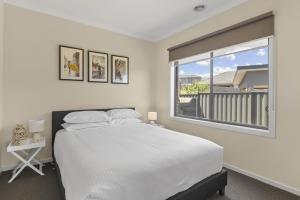 a white bedroom with a large bed and a window at Family Retreat with Garden and Parking in Melbourne
