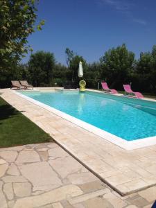 a swimming pool with pink chairs in a yard at A Casa di Diamante in Bisceglie