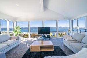 een woonkamer met banken, een tv en ramen bij Seaview Home in Khandallah in Wellington