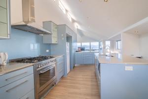 een keuken met witte kasten en een kookplaat oven bij Seaview Home in Khandallah in Wellington