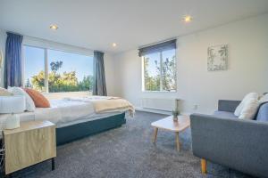 een slaapkamer met een bed, een bank en ramen bij Seaview Home in Khandallah in Wellington