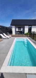 a large blue swimming pool in front of a house at Relaxing coastal home with pool and spa in Papamoa