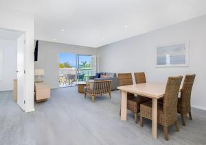 Un comedor y una sala de estar con mesa y sillas. en One-Bedroom Lagoon Spa Apartment, en Salamander Bay