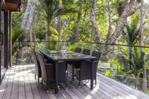Waiheke IslandにあるTe Toki Treehouse and Studioの木の茂るデッキ(黒いテーブルと椅子付)