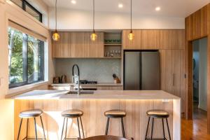 a kitchen with wooden cabinets and a large island with bar stools at Te Toki Treehouse and Studio in Waiheke Island