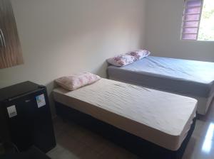 a room with two beds and a small refrigerator at Casa Freire in Lavras