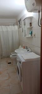 a bathroom with a washing machine and a toilet at Sara's House in Minas