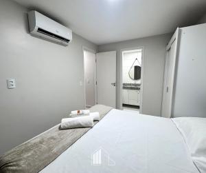 a bedroom with a large white bed and a tv at Apartamento na Praia dos Milionários - 100M do Mar in Cururupe +18 photos