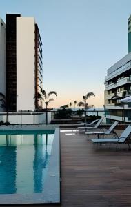a swimming pool with lounge chairs and a building at Apartamento na Praia dos Milionários - 100M do Mar in Cururupe