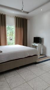 a bedroom with a large bed and a large window at Família Freitas in Ananindeua
