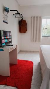 a bedroom with a desk with a computer and a red rug at Família Freitas in Ananindeua