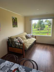 a living room with a couch and a window at Cabañas Los Aromos de Puerto Varas in Puerto Varas