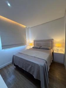 a bedroom with a large bed with two lamps on it at Alto padrão com ar, garagem, sacada integrada in Belém