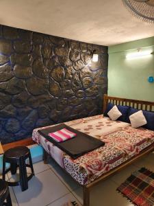 a bedroom with a bed and a stone wall at CLOUD HUG'S COUPLES STAY Rooms Vagamon in Vagamon