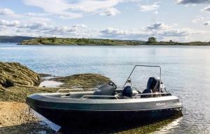 a boat parked on the shore of a body of water at Gorgeous Home In Søgne With Wifi in Søgne +12 photos