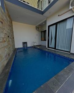 une grande piscine avec de l'eau bleue dans un immeuble dans l'établissement Villa Almaria, à Batu