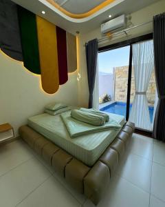 un lit dans une chambre avec une grande fenêtre dans l'établissement Villa Almaria, à Batu 8 autres photos