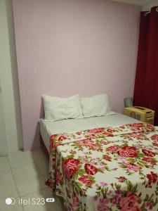 a bedroom with a bed with a floral blanket on it at Casa da Josse in Camaçari +17 photos