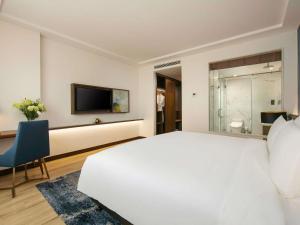 a bedroom with a large white bed and a tv at Mövenpick Living West Hanoi in Hanoi +177 photos