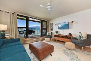 a living room with a blue couch and a table at Kaleialoha 210 · KA 210 OceanFront 1BD Tropical Getaway w AC in Kahana