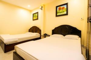 two beds in a hotel room with white sheets at Cát Tường Hotel in Ho Chi Minh City