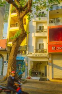a person riding a motorcycle next to a tree at Cát Tường Hotel in Ho Chi Minh City