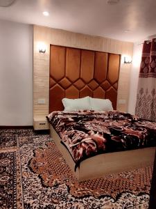 a bedroom with a large bed with a wooden headboard at Residence Inn Home Stay in Pahalgām