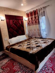 a bedroom with a large bed with a red headboard at Residence Inn Home Stay in Pahalgām