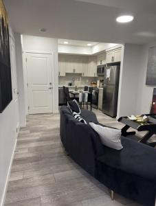 Una sala de estar con un sofá negro y una cocina. en Luxury Haven by Kc & Flo, en Calgary